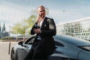 Erfolgreicher Unternehmer telefoniert vor einem Porsche, symbolisch für den Erfolg durch Lean Management Methoden.